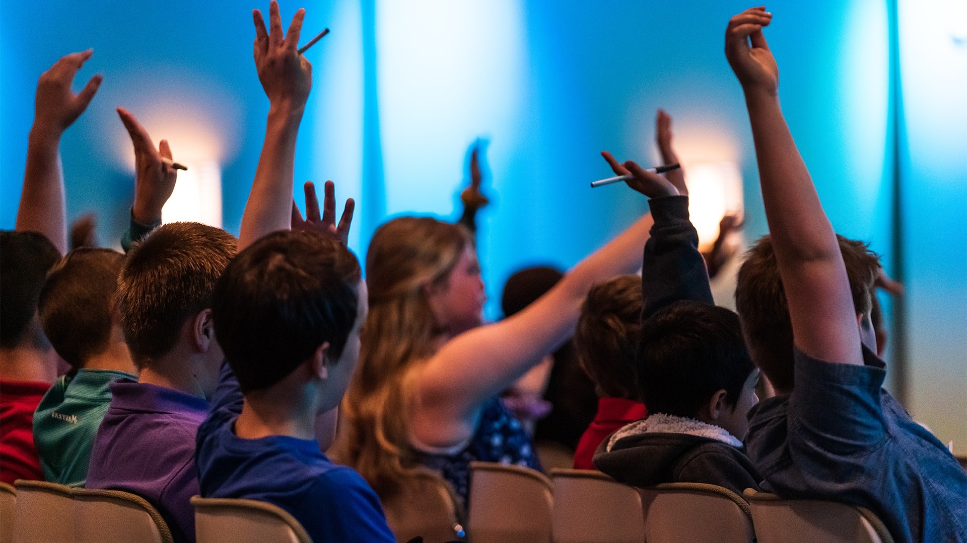Students raise their hands at a Sunday meeting at Brookwood Church